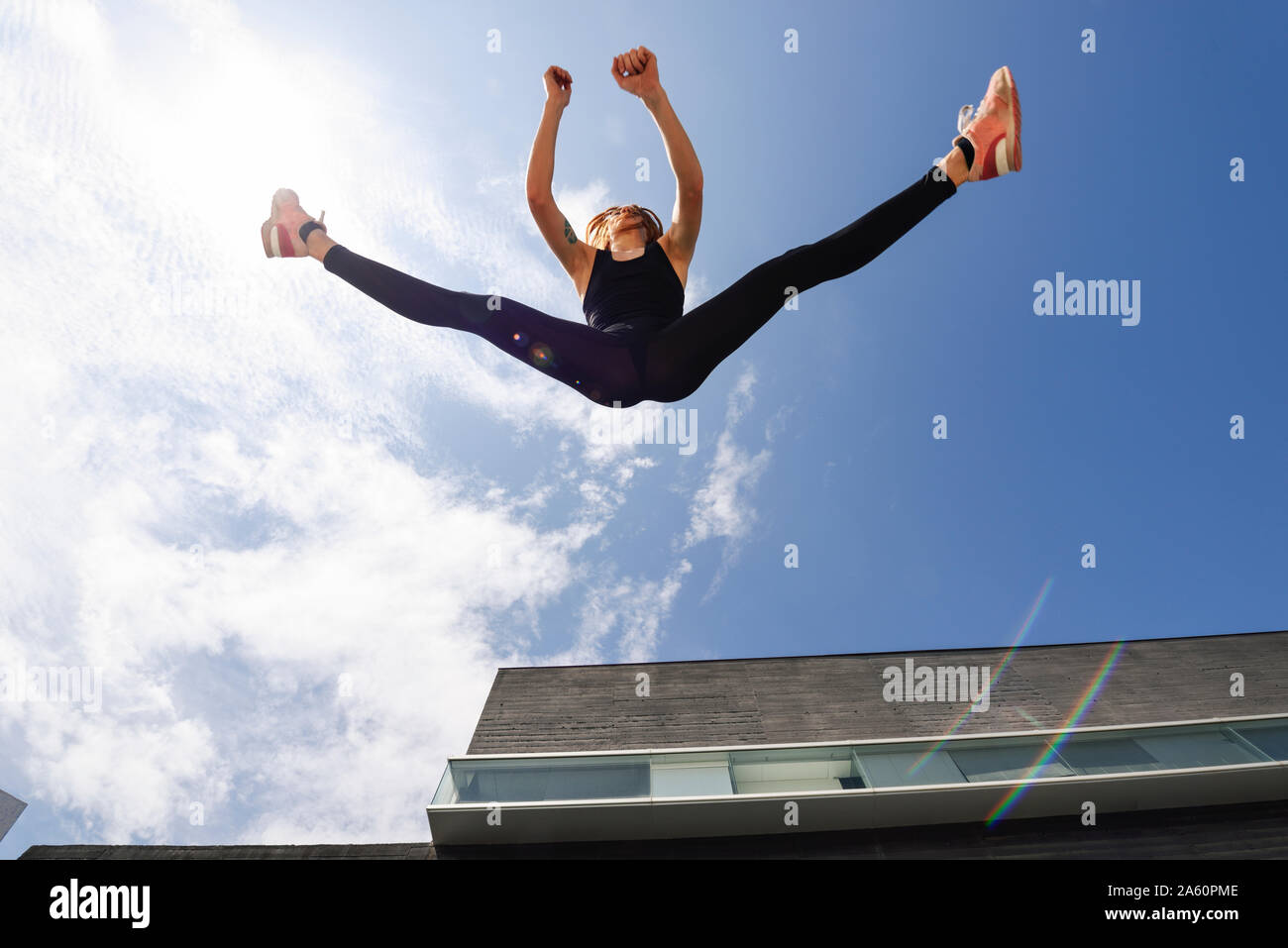 Sporty giovane donna salta all'aperto alla luce diretta del sole Foto Stock