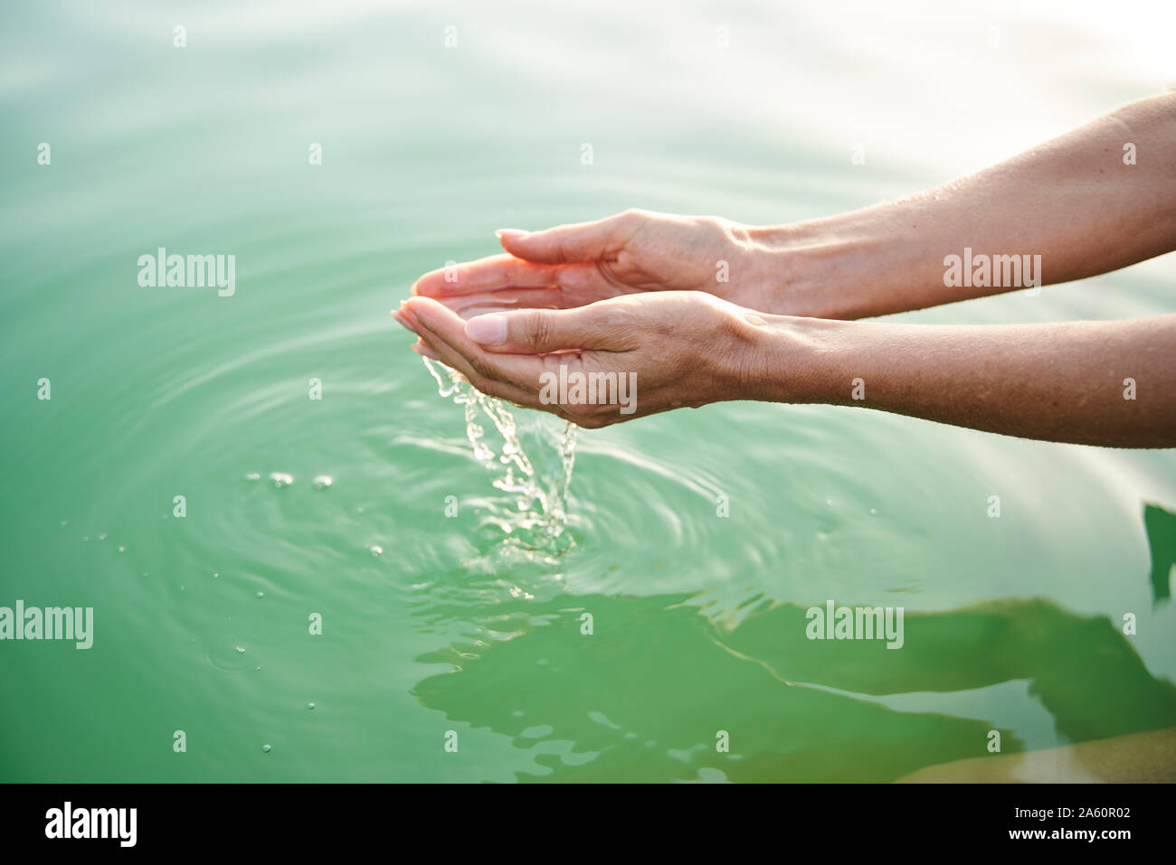 Close-up di donna di mani toccano acqua di lago Foto Stock