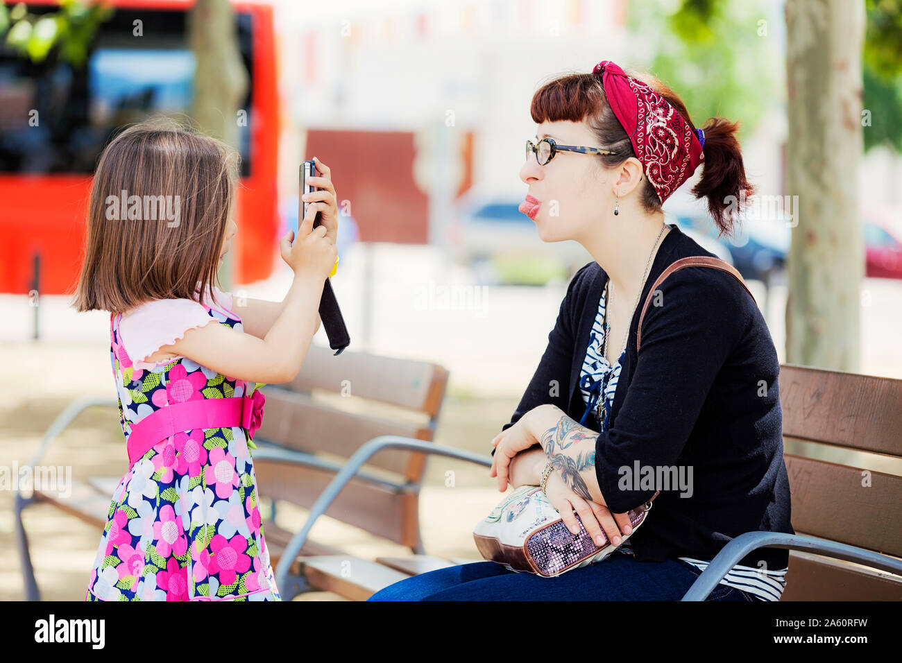 Bambina prendendo foto di sua madre con lo smartphone Foto Stock