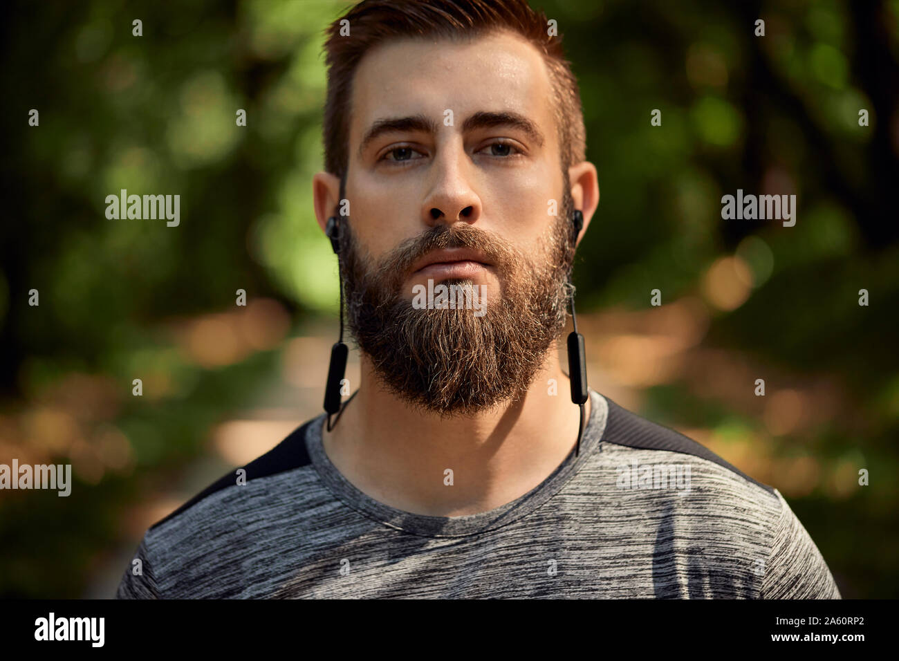 Ritratto di uomo sportivo con gli auricolari in foresta Foto Stock