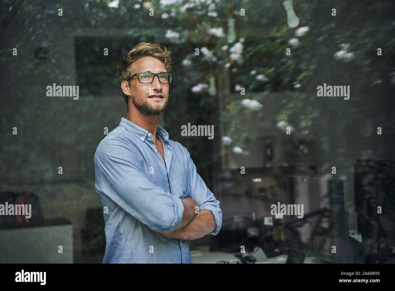 Casual giovane imprenditore dietro il vetro di finestra di office Foto Stock