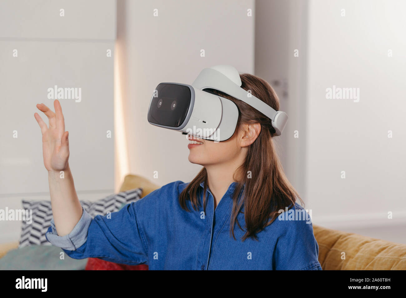 Giovane donna utilizzando occhiali VR a casa Foto Stock
