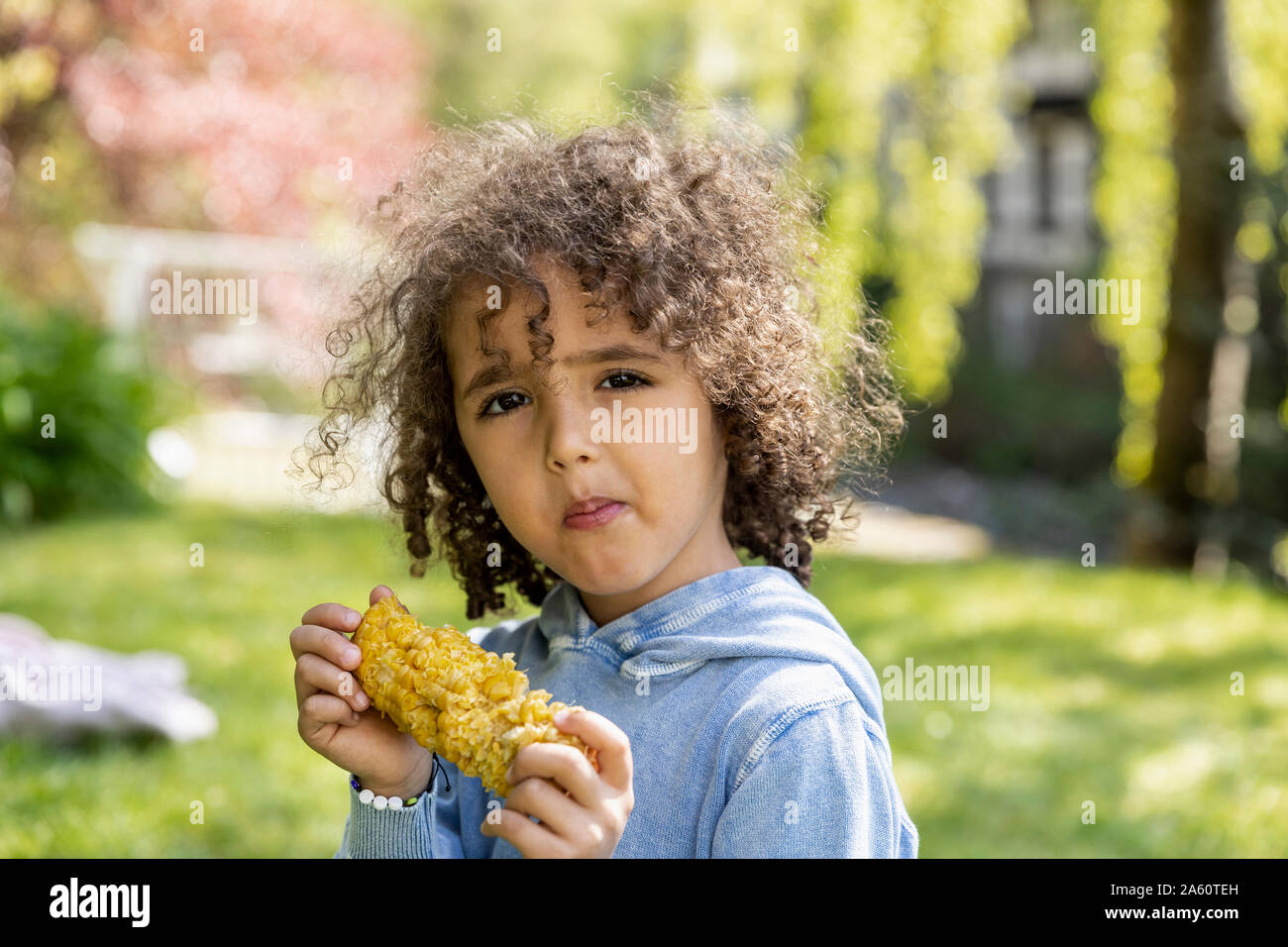 Ritratto di ragazzo di mangiare una pannocchia in giardino Foto Stock