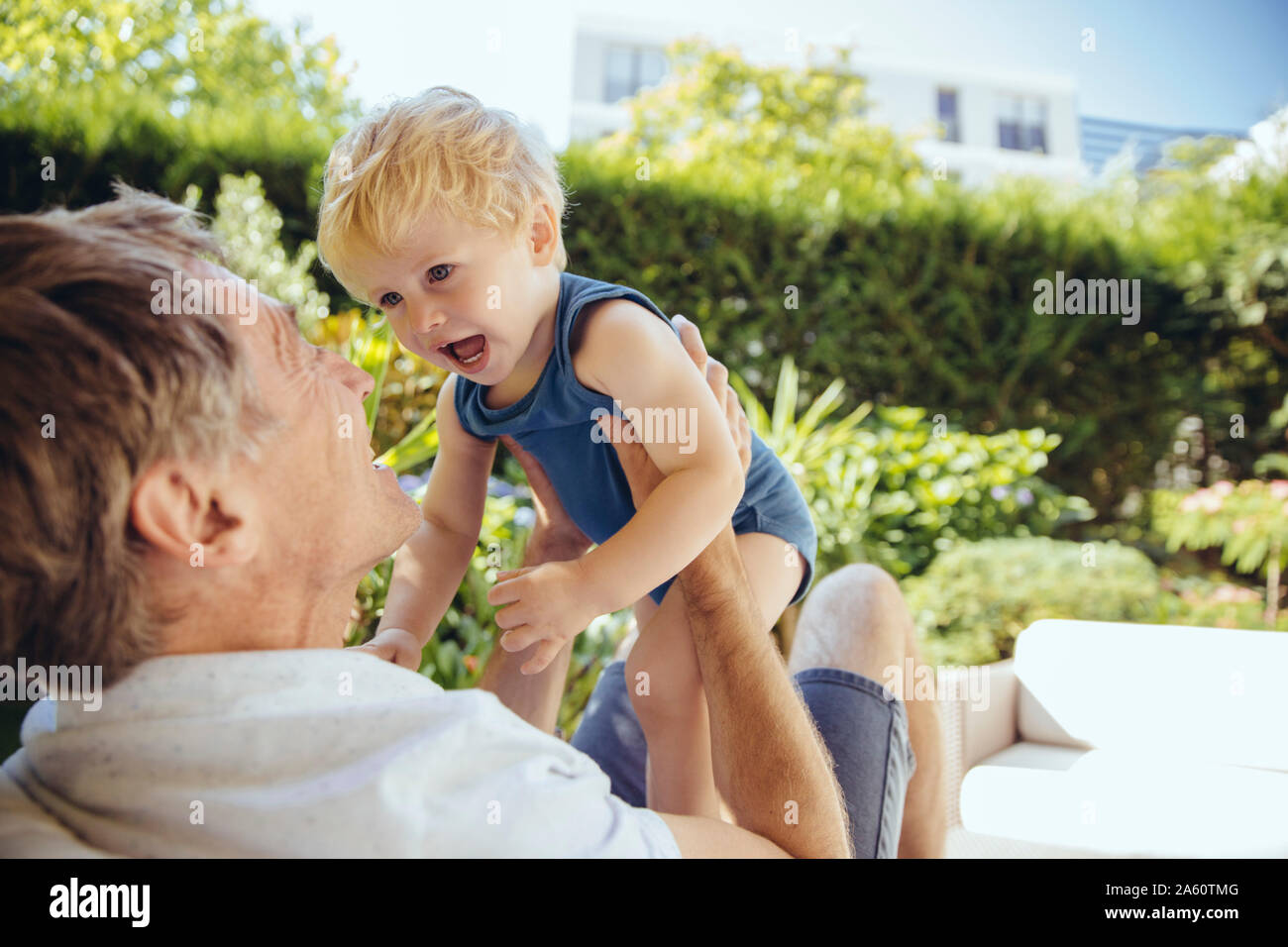 Padre seduti in giardino, giocando con il suo piccolo figlio Foto Stock