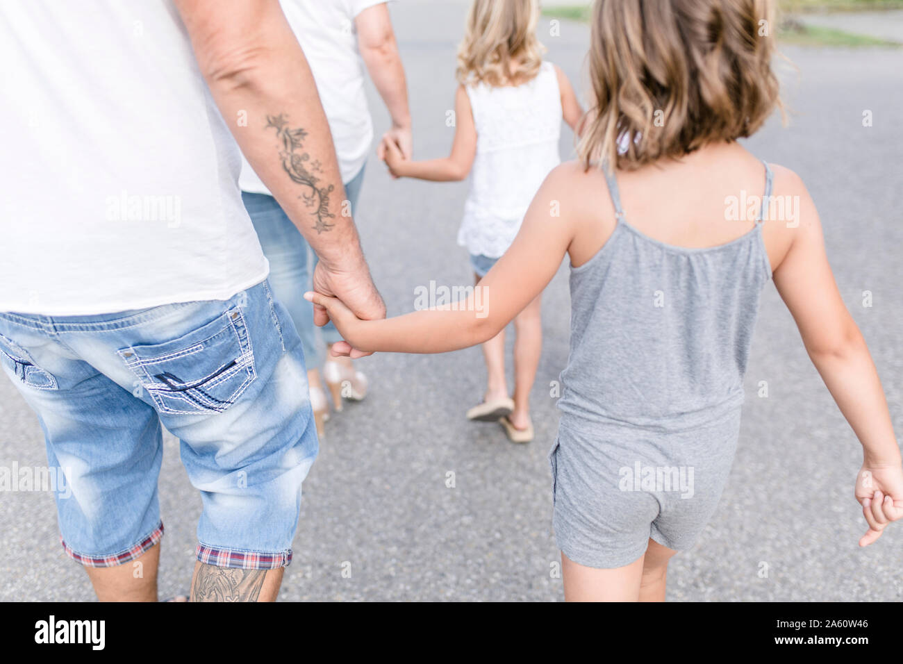 Vista posteriore della famiglia camminando mano nella mano su una strada Foto Stock