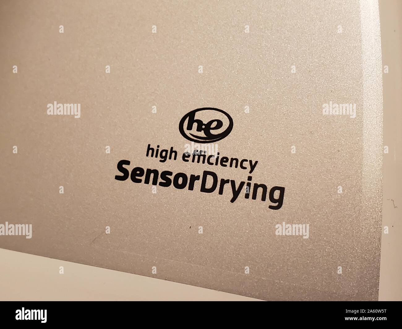 Primo piano del logo HE, o High Efficiency, su un essiccatore di abbigliamento domestico, che certifica che la macchina è in grado di utilizzare la tecnologia dei sensori per ridurre i tempi di asciugatura e risparmiare energia, San Ramon, California, 13 agosto 2019. () Foto Stock
