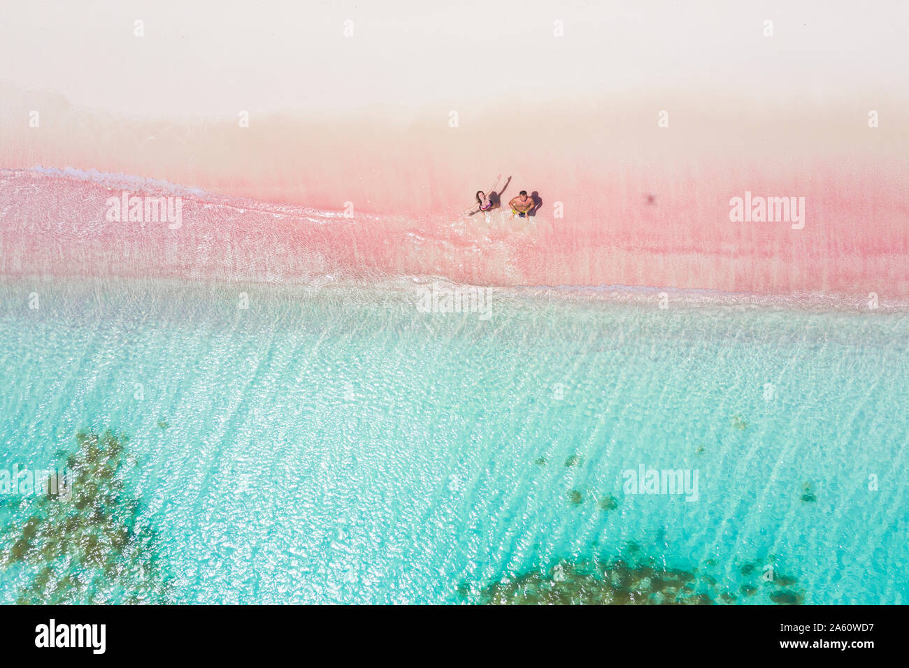 L uomo e la donna per divertirsi a volare un drone sulla sabbia rosa beach, Caraibi, Antille, West Indies, America Centrale Foto Stock