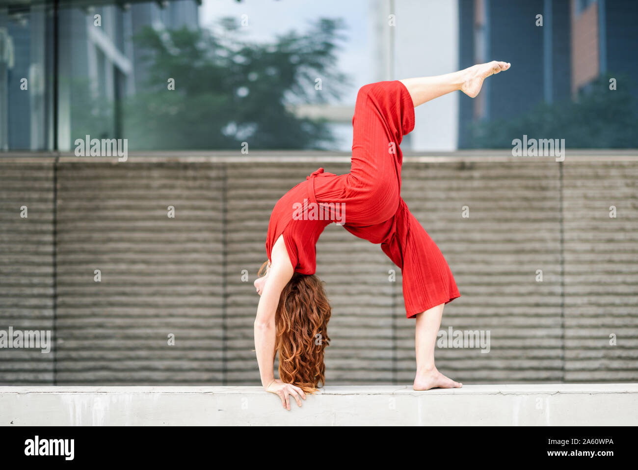 Sporty giovane donna facendo acrobazie su un muro di cemento Foto Stock