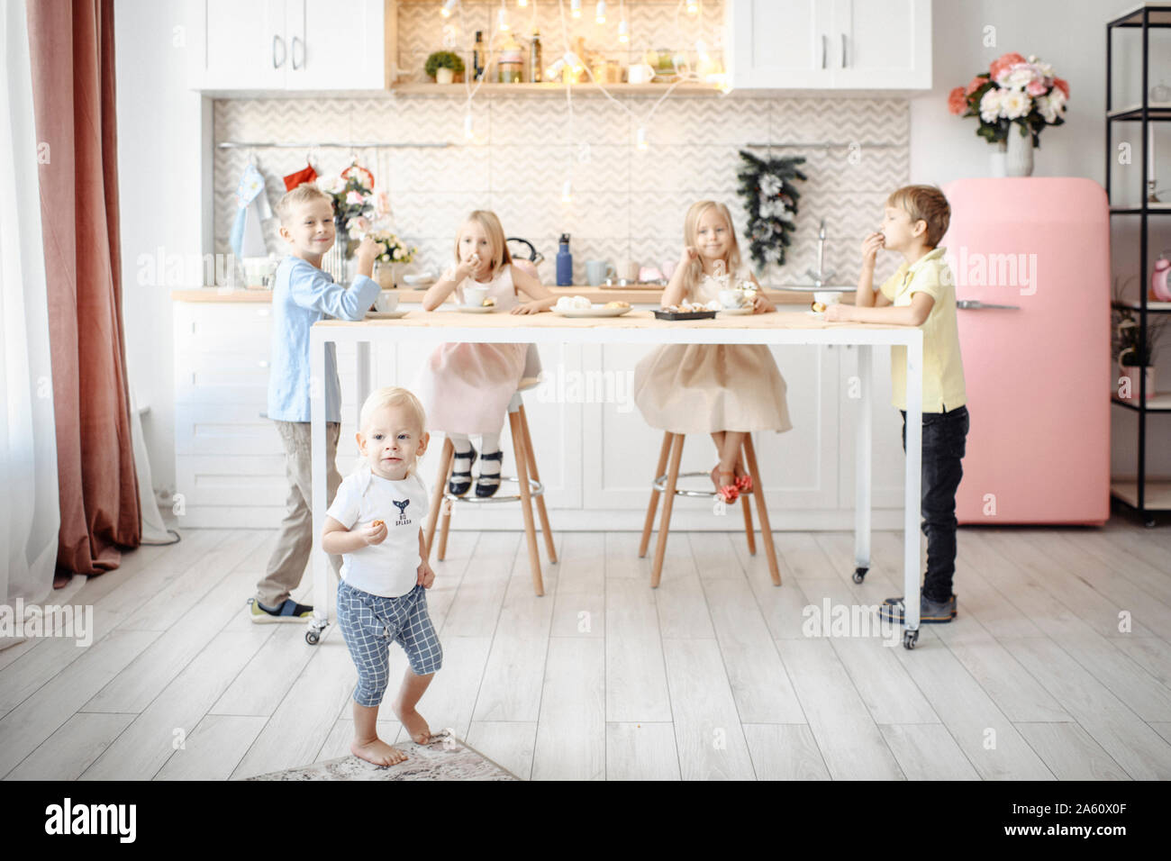 Fivechildren mangiare i cookie in cucina Foto Stock