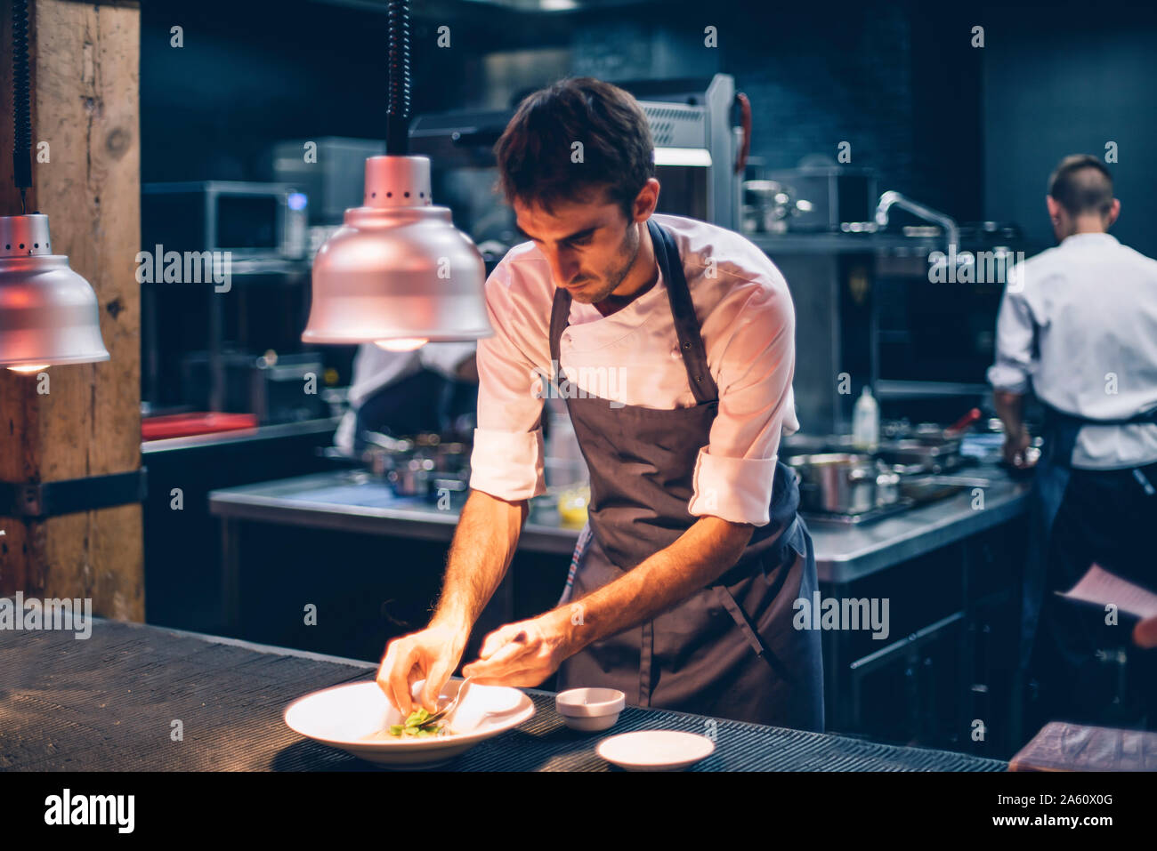 Lo chef serve cibo su una piastra nella cucina di un ristorante Foto Stock