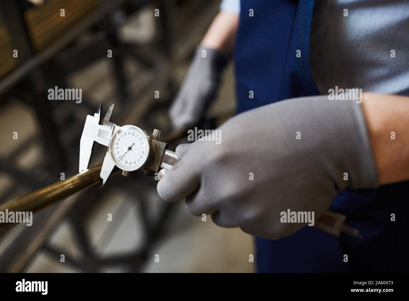 Close-up del lavoratore in guanti di protezione tenuta tubo di ferro e la si misura con uno speciale strumento di misurazione Foto Stock