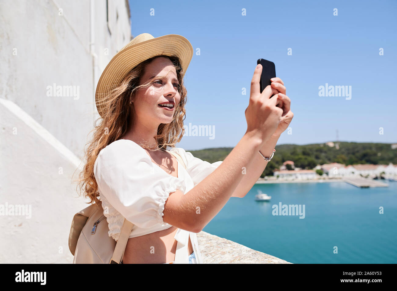 Giovane donna prendendo un selfie presso la costa, Menorca, Spagna Foto Stock