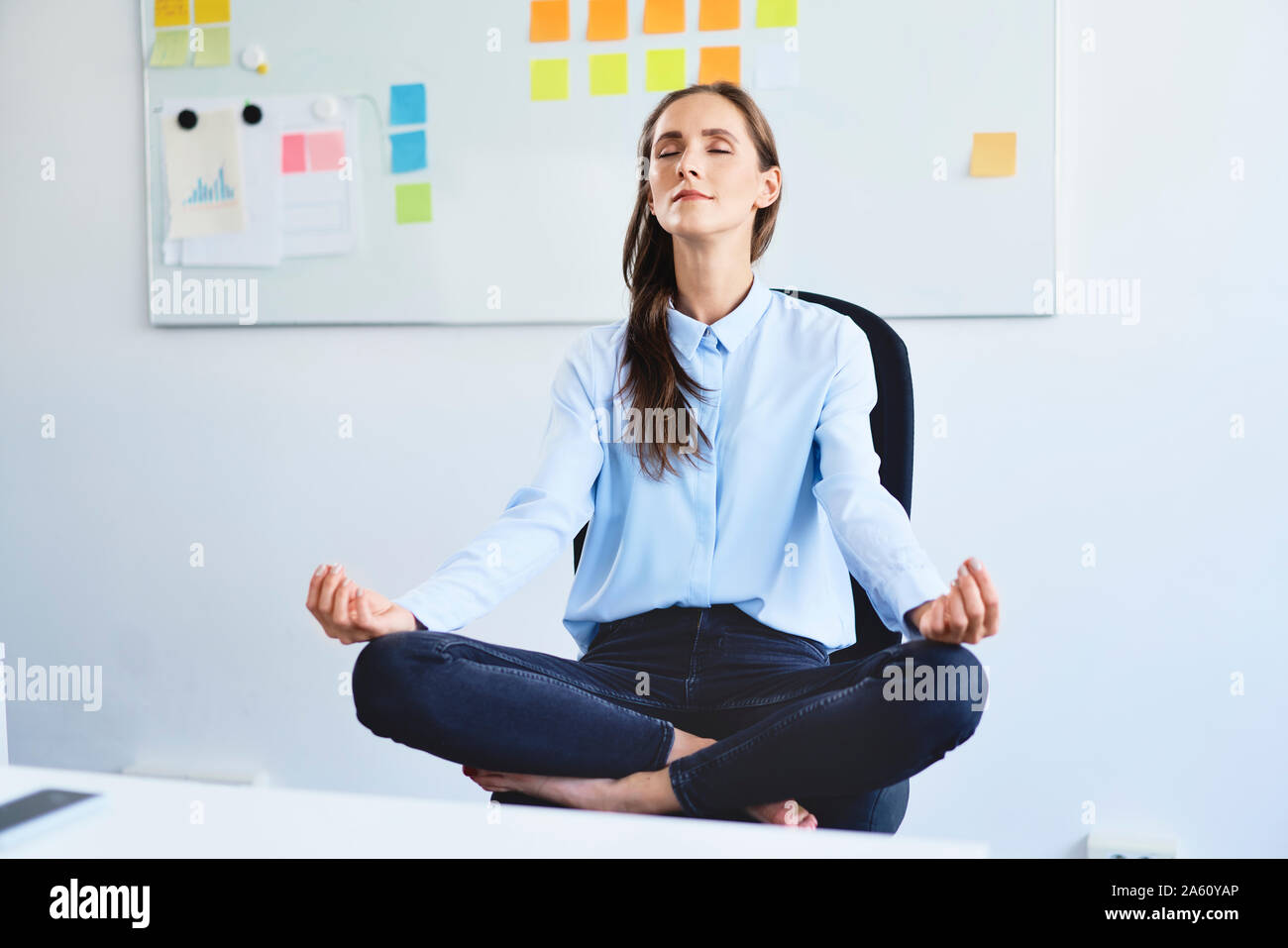 Giovane imprenditrice seduto sulla sedia da ufficio meditando Foto Stock
