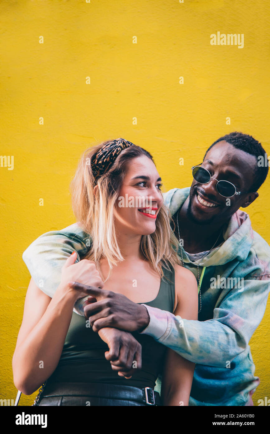 Ritratto di coppia felice nella parte anteriore della parete gialla Foto Stock