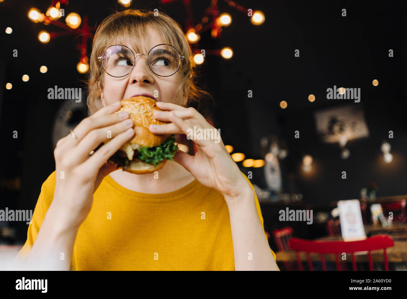 Giovane donna di mangiare hamburger in un ristorante Foto Stock
