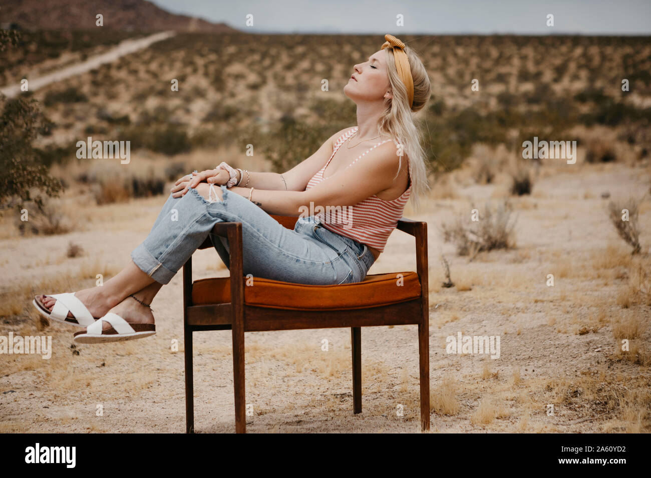 Donna seduta su una sedia nel paesaggio del deserto, Joshua Tree National Park, California, Stati Uniti d'America Foto Stock