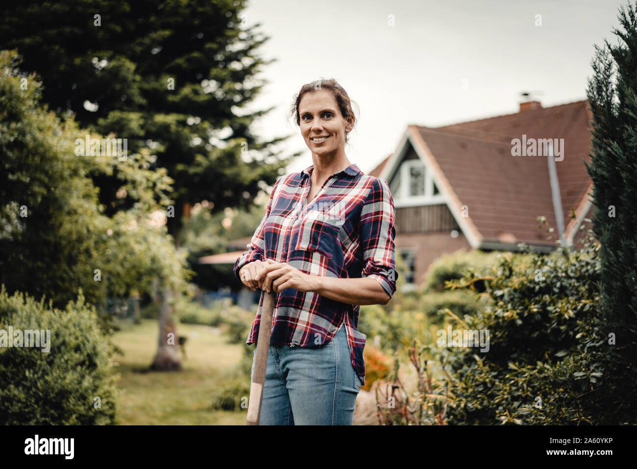 Orgoglioso proprietario di casa in piedi nel suo giardino con una vanga Foto Stock