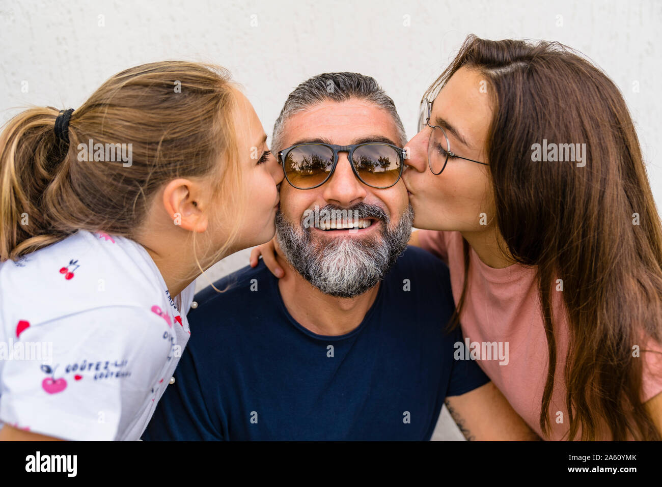 Due figlie baciare padre felice Foto Stock