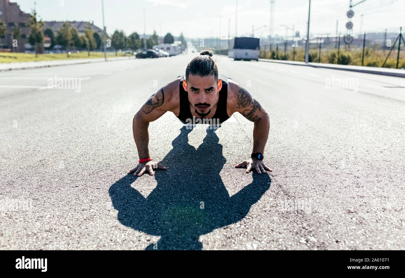 Giovane uomo che fa spingere ups su una strada Foto Stock