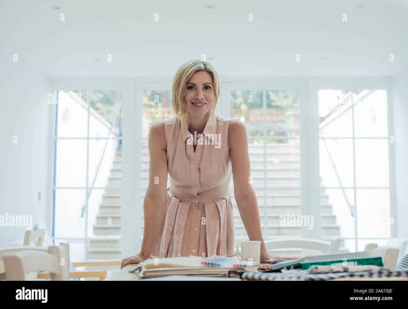 Ritratto di donna imprenditore in piedi vicino i campioni di tessuto e di design di moda su tavola Foto Stock