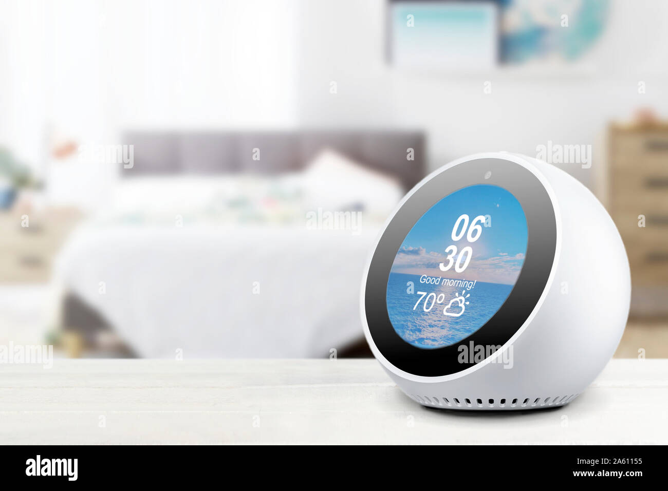 Assistente personale sveglia e un altoparlante su un bianco ripiano in legno di una casa intelligente in camera da letto. Svuotare lo spazio di copia per l'editor di testo. Foto Stock