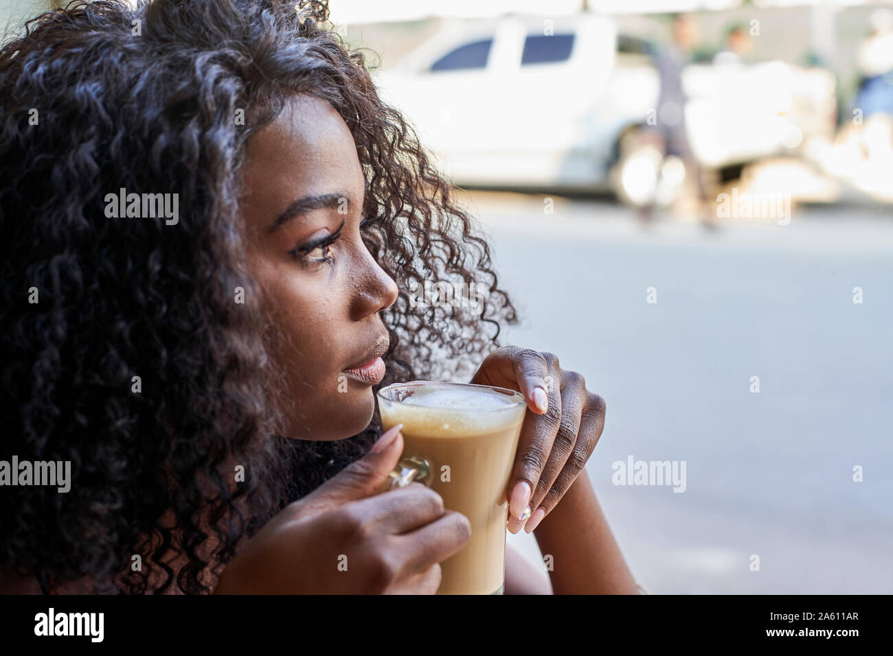 Ritratto di giovane donna africana in un caffè guardando fuori della finestra Foto Stock
