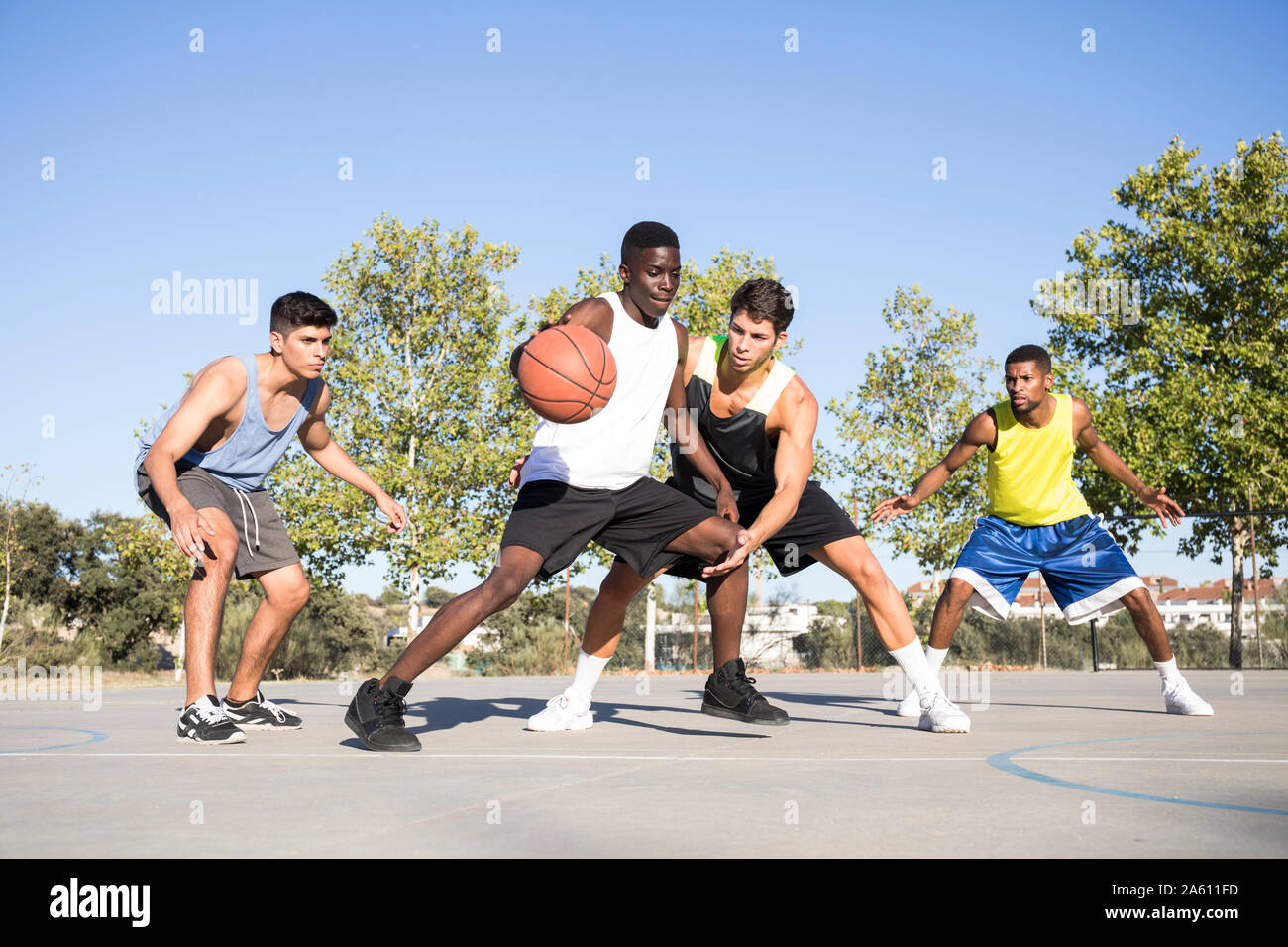 Giovani uomini giocare a basket e dribbling palla sul campo sportivo Foto Stock