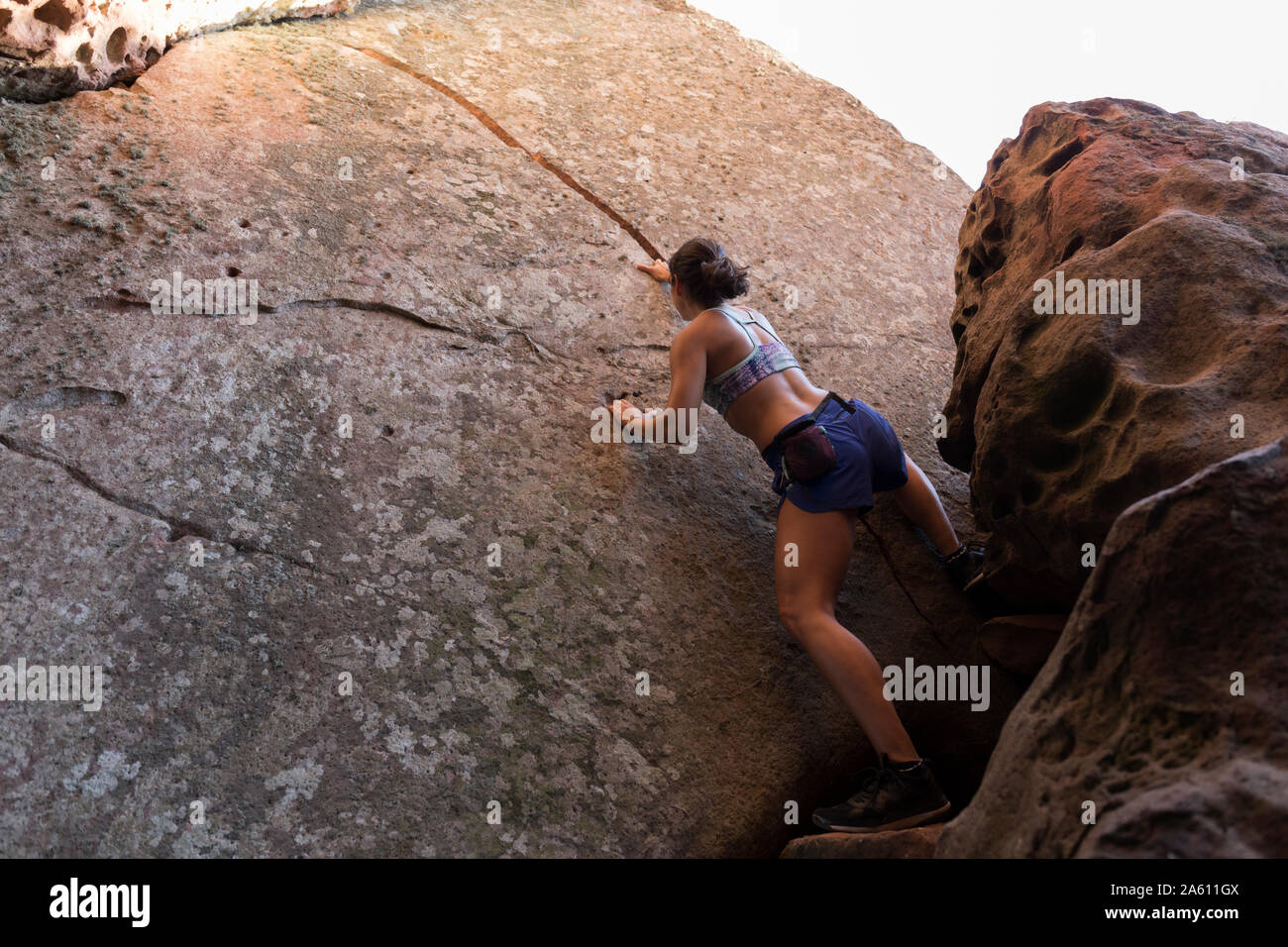 Giovane donna asiatica di arrampicata in una parete di roccia Foto Stock