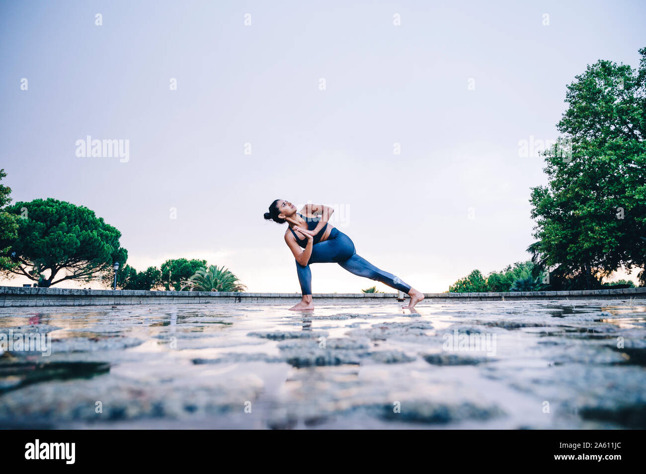 Donna pratica lo yoga sotto la pioggia, triangolo pongono Foto Stock
