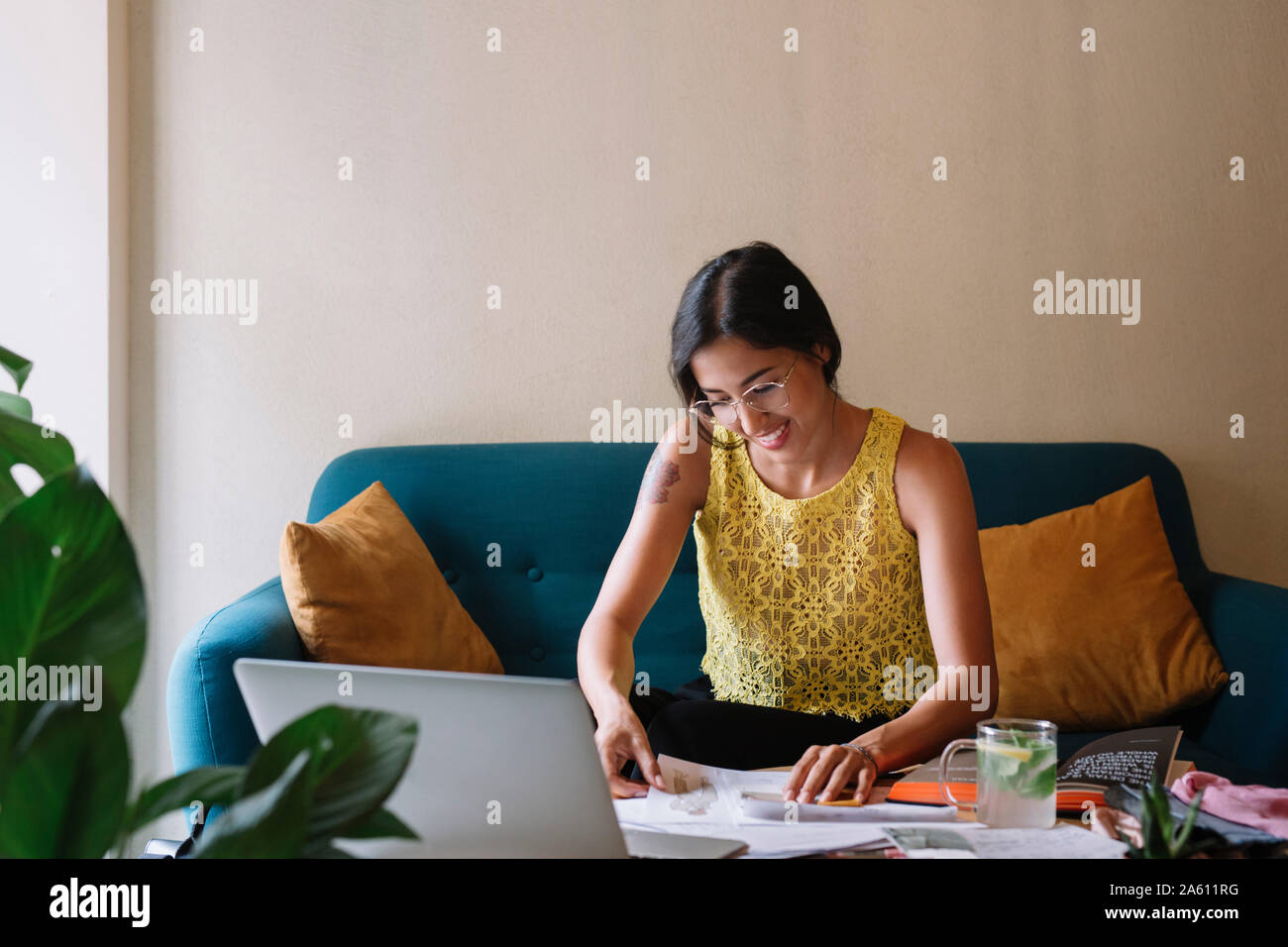 Sorridente fashion designer seduta sul lettino lavorando su una nuova collezione Foto Stock