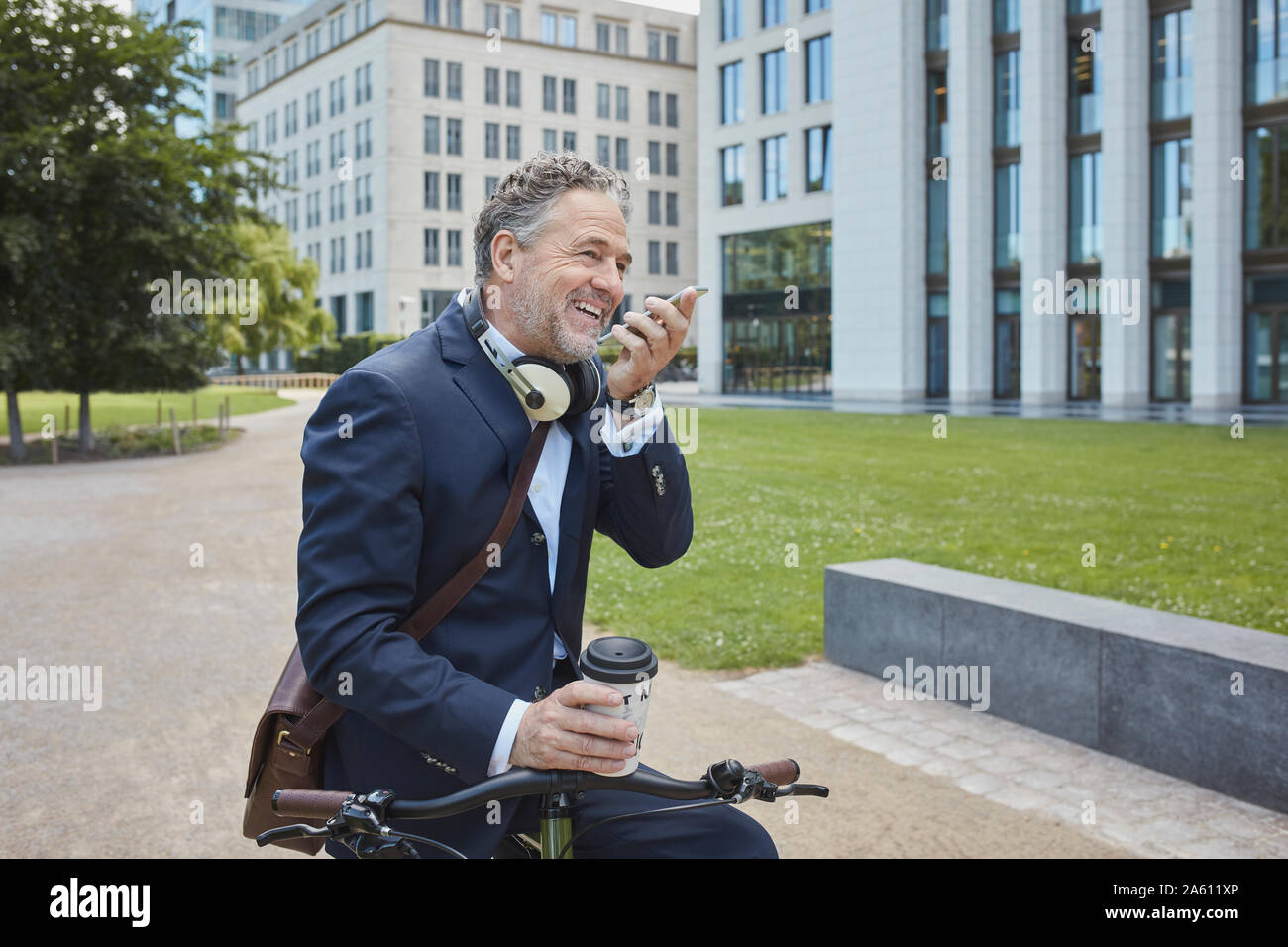 Imprenditore maturo con bicicletta utilizza lo smartphone nella città Foto Stock