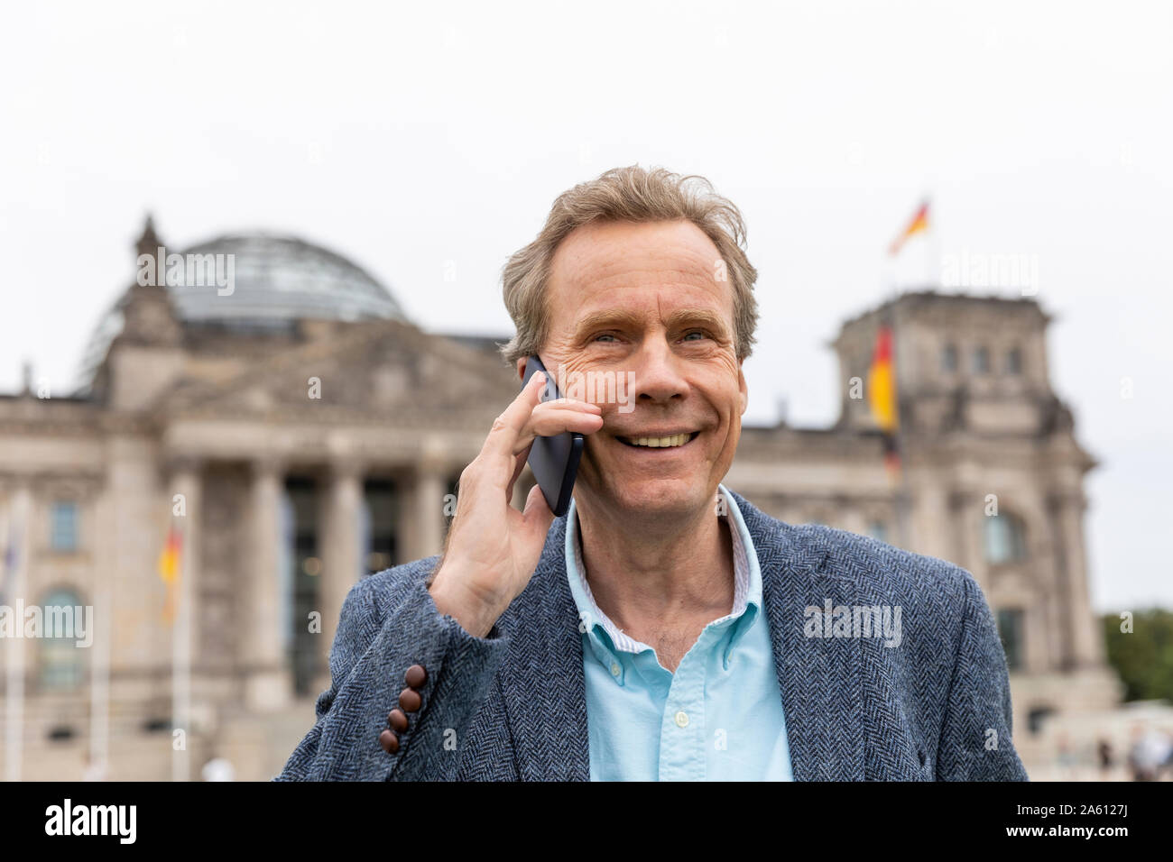 Ritratto di sorridente uomo senior sul telefono cellulare al Reichstag di Berlino, Germania Foto Stock