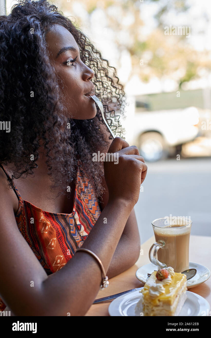 Ritratto di giovane donna africana di mangiare un pezzo di torta e un caffè Foto Stock