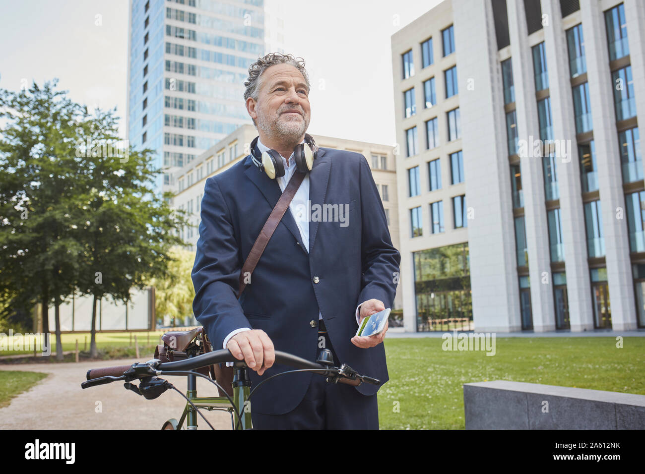 Imprenditore maturo con la bicicletta in città Foto Stock