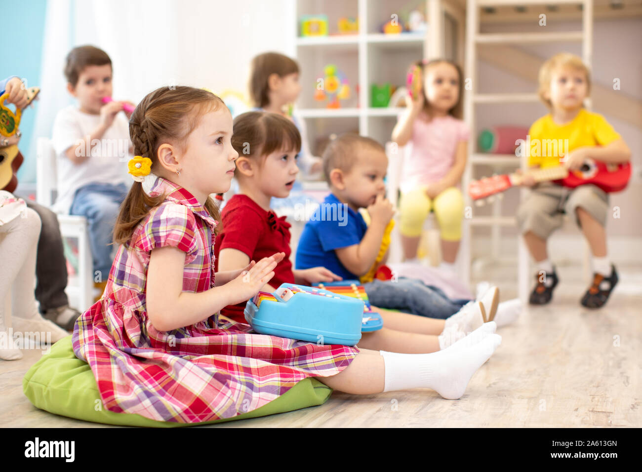 Gruppo di bambini da 3 a 4 anni con strumenti musicali giocattolo. Inizio educazione musicale nella scuola materna Foto Stock