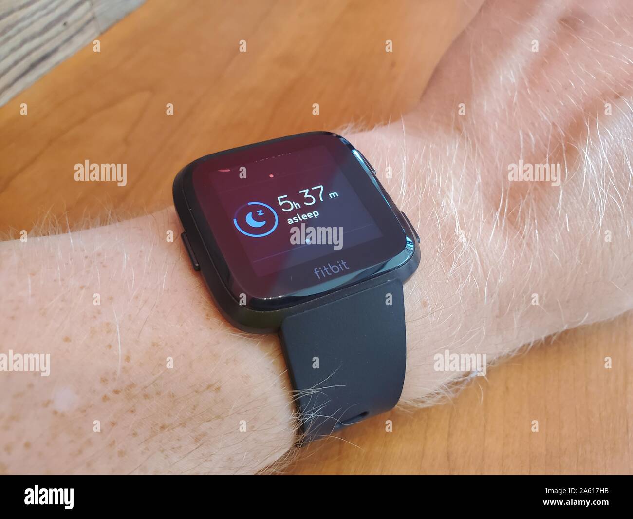 Primo piano di un braccio di un uomo che indossa un orologio intelligente  Fitbit Versa che visualizza i dati di monitoraggio del sonno, una capacità  recentemente ampliata di diversi prodotti Fitbit, San