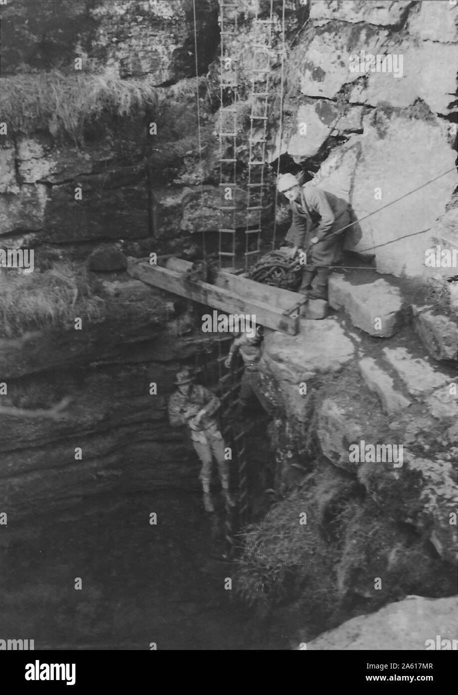 Due uomini usano l'arrampicata primitiva e l'attrezzatura per scendere nella bocca di una grotta durante un Northern Cavern e Fell Club arrampicata e speleologia evento nello Yorkshire, Regno Unito, 1934. () Foto Stock