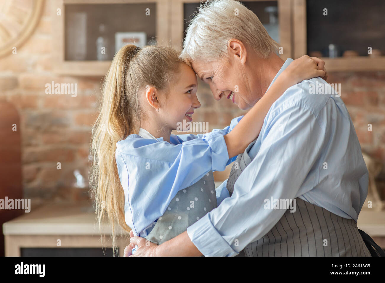 Piccolo nipote abbracciando la sua nonna felice in cucina Foto Stock