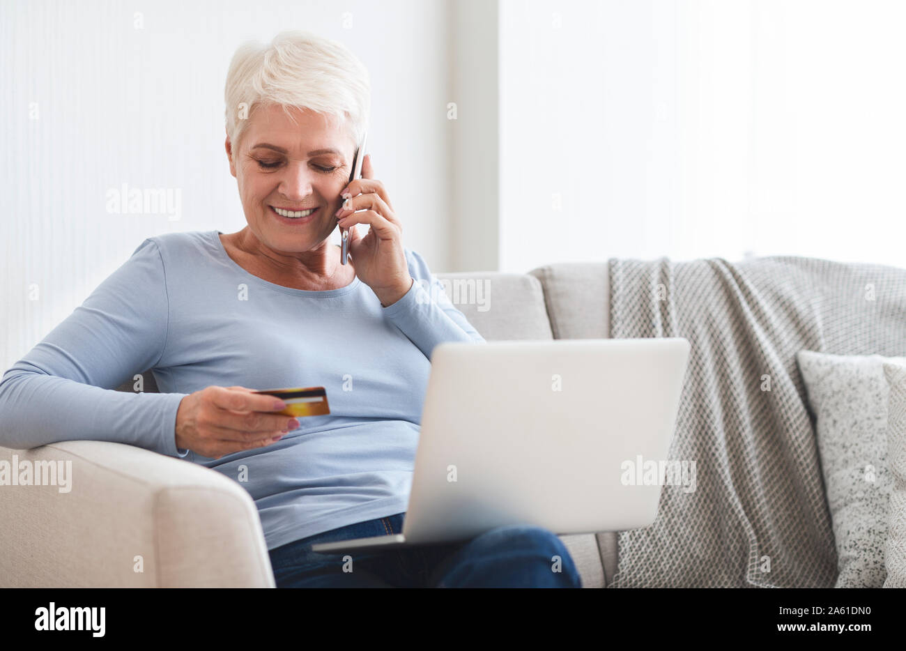 Old Lady acquisto on-line, controllando il numero della sua carta di credito Foto Stock