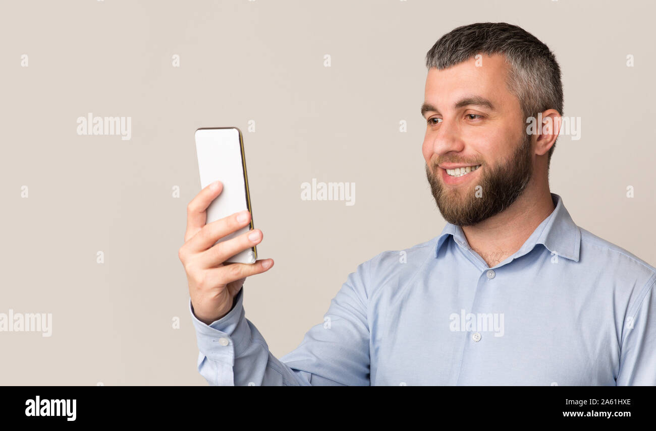 Uomo sorridente con il riconoscimento facciale su smartphone moderno Foto Stock