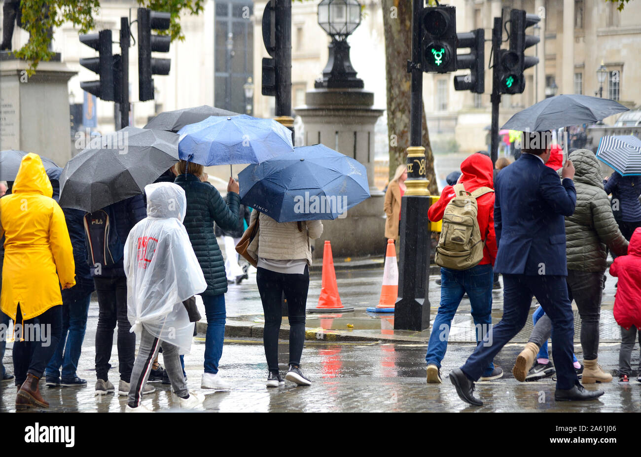 Londra, Inghilterra, Regno Unito. Persone con ombrelloni in Trafalgar Square in un giorno di pioggia Foto Stock
