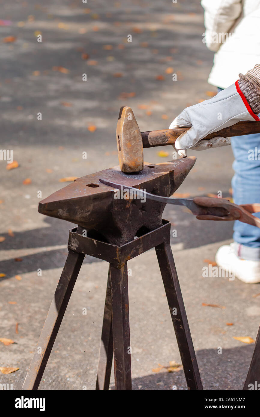 Un fabbro forgia uno sbozzato metallico sull'incudine ad una fiera in  presenza di spettatori. Fabbro medievale forge soffietto. Metallurgico di  fusione del ferro Foto stock - Alamy