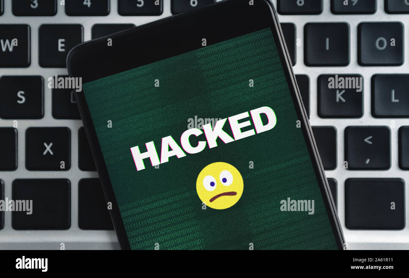Smartphone con hacked iscrizione e triste icona emoji sullo schermo Foto Stock