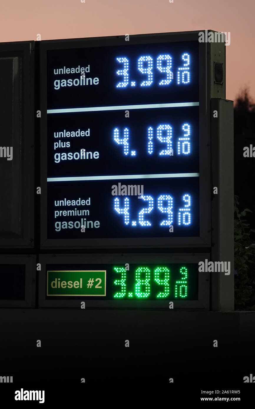 Un digital gas station segno mostra la corrente i prezzi del carburante accanto a una strada negli Stati Uniti durante la sera. Foto Stock