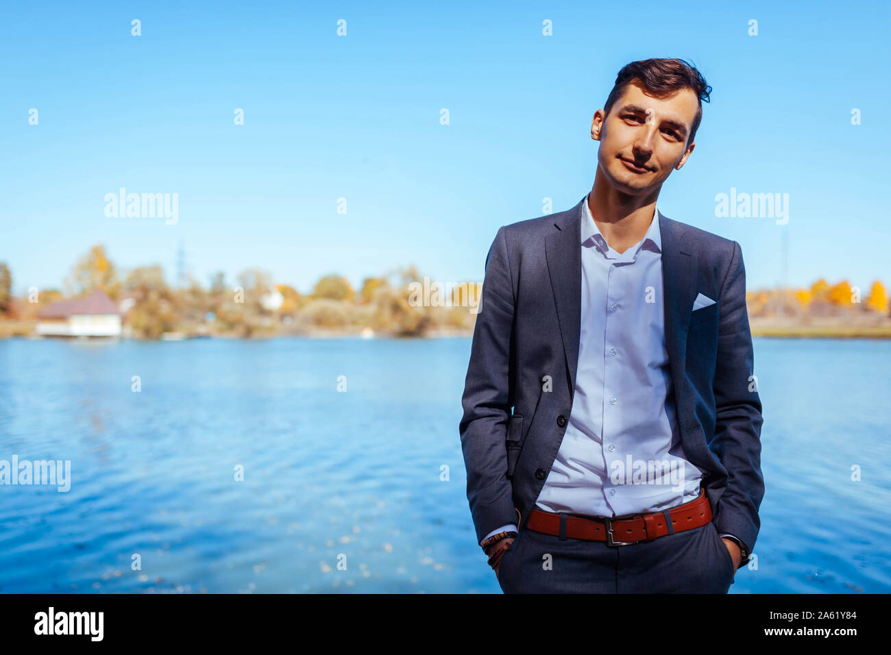Maschio moda autunno. Uomo bello indossare tuta grigio e accessori esterni. Ritratto di giovane ragazzo in abiti eleganti Foto Stock