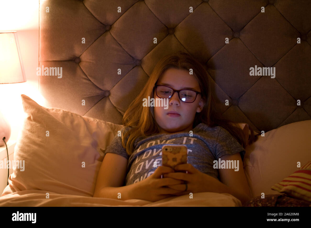 Ragazza giovane texting amici prima di andare a letto tempo Foto Stock