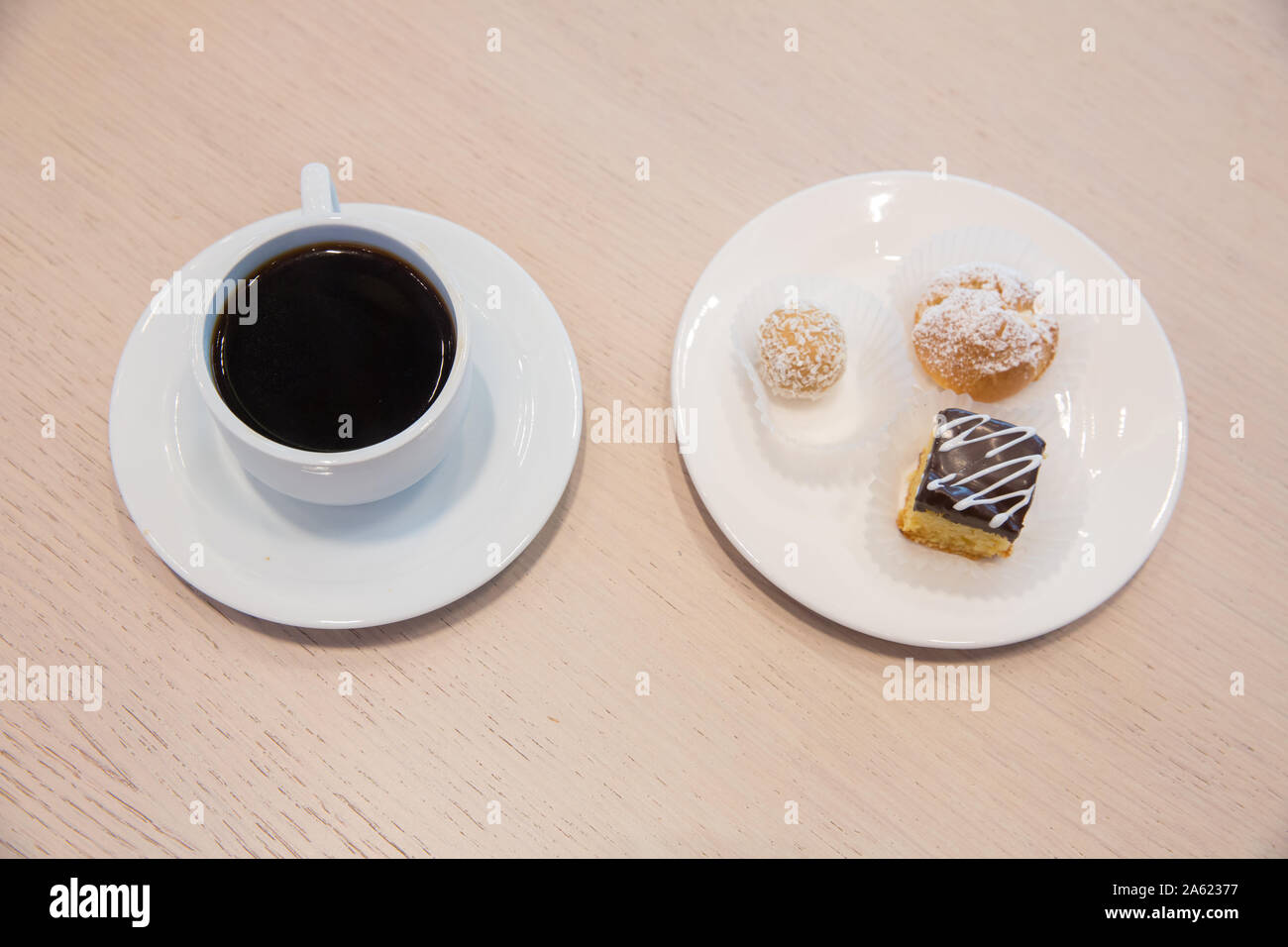 Fetta di tre torta al cioccolato decorata con petali di cioccolato, sulla piastra bianca su sfondo bianco. Torta all'interno della piastra bianca . Foto Stock