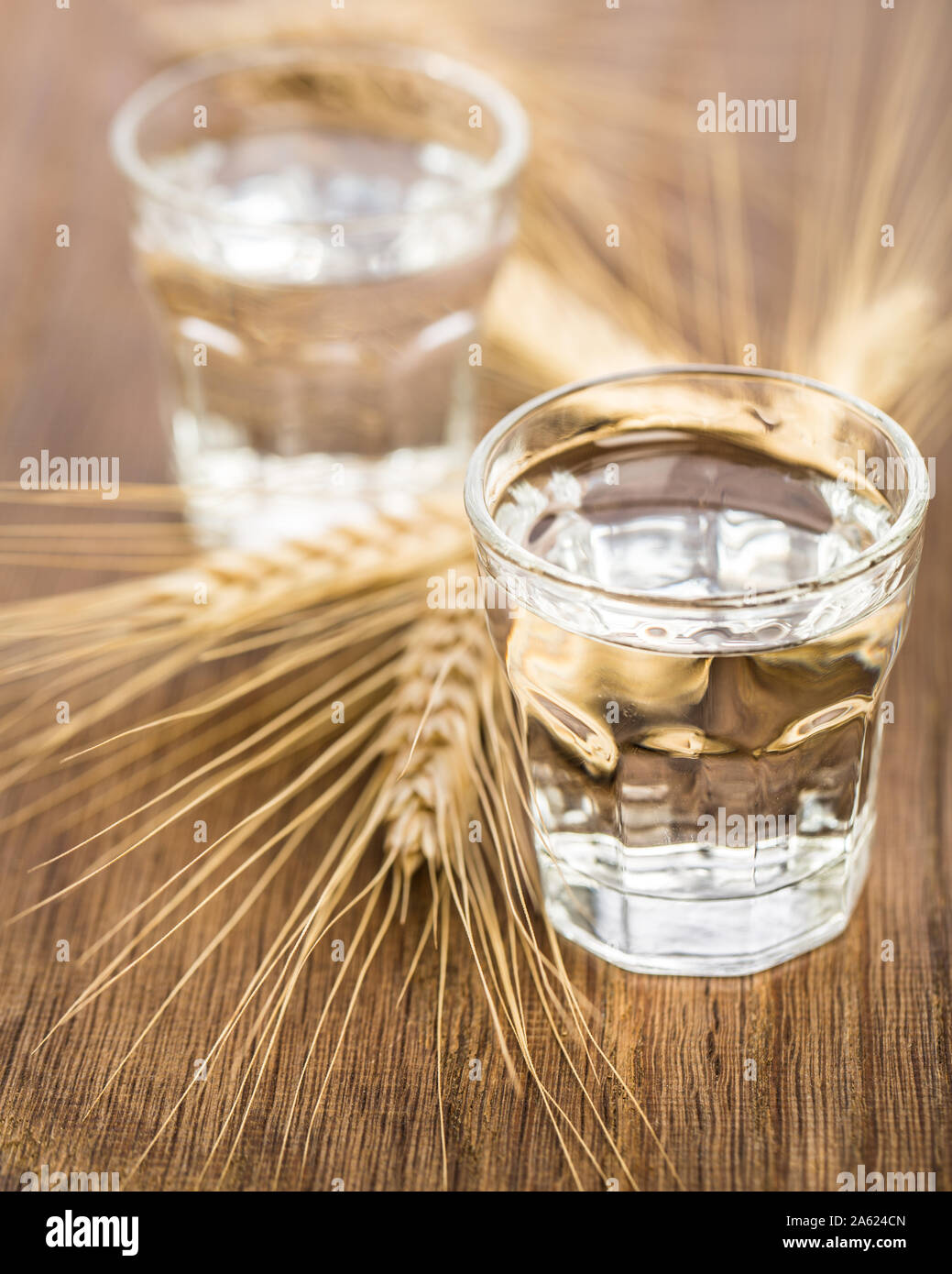 Due bicchieri con la grappa di mais e grano insieme sullo sfondo di legno Foto Stock