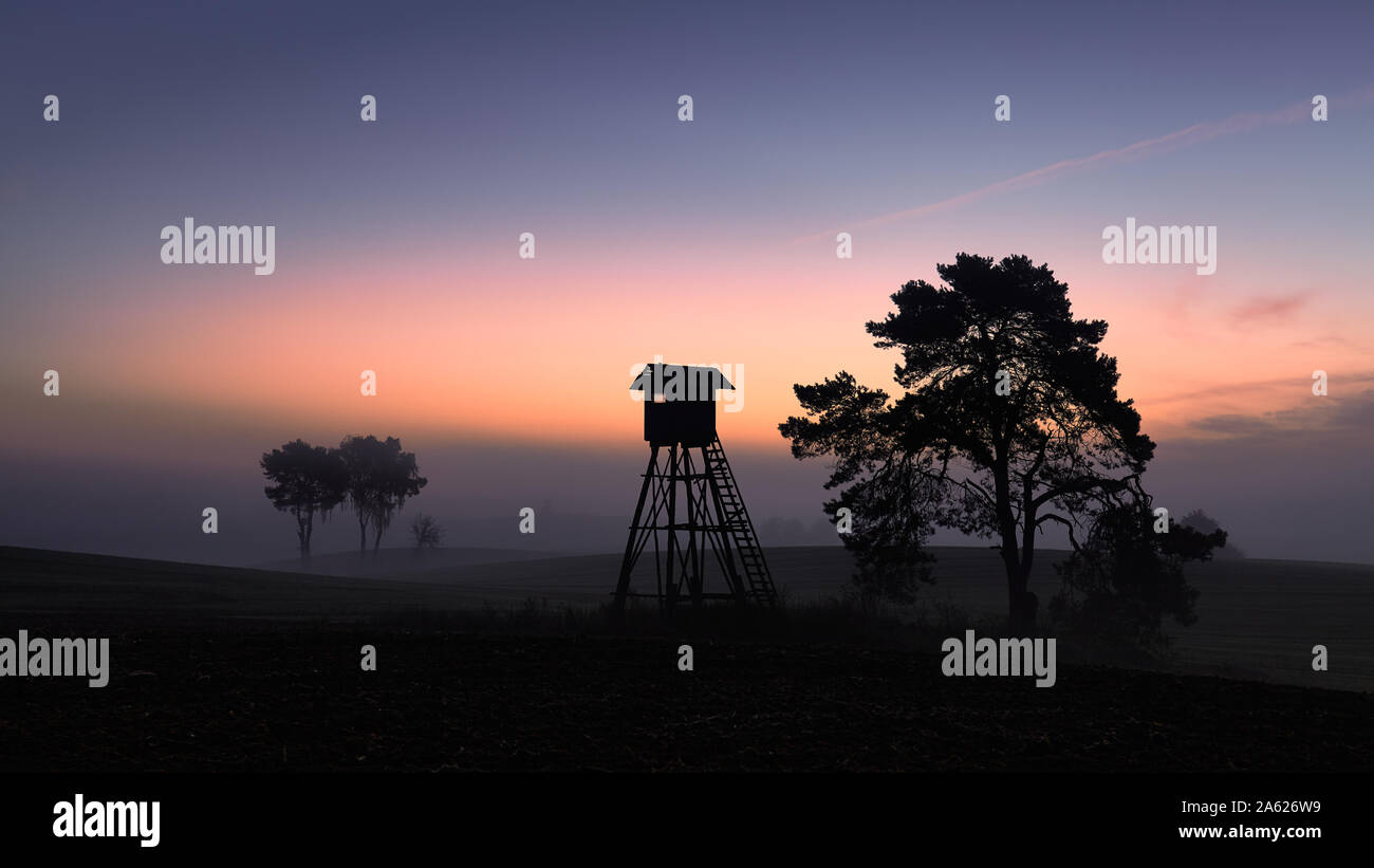 Silhouette di una torre di caccia su un campo in all'alba. Foto Stock