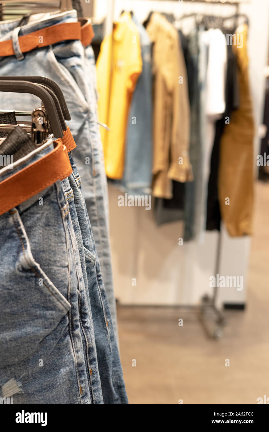 Jeans blu su un appendiabiti in primo piano una dressing room in background. Memorizzazione di cose. Foto Stock